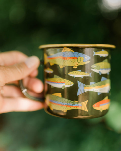 Trout Mug - Enamel 16oz Mug with colorful trout design, perfect for hot or cold beverages, held outdoors.