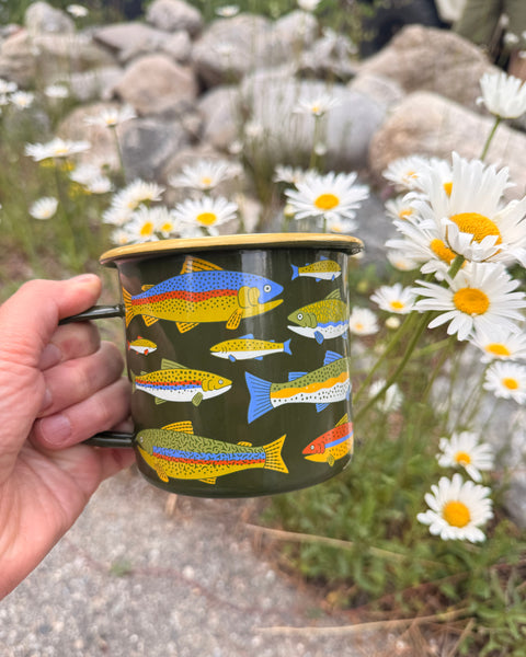 Trout Mug - Enamel 16oz Mug held in hand with colorful trout design amidst daisies.