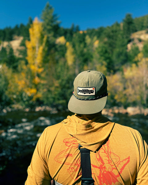 Person wearing a Trout Hat (Olive) while enjoying a day outdoors by the river.