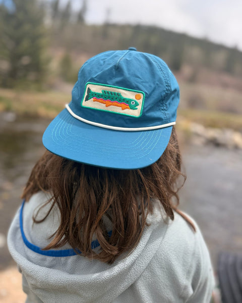 Trout Kids Hat worn by child outdoors near water, combining style and comfort for little adventurers.