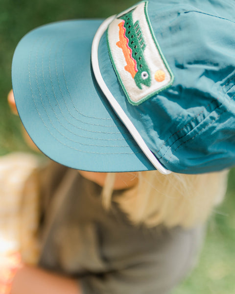 Trout Kids Hat worn by a child outdoors, featuring a fun trout design and lightweight material for comfort.
