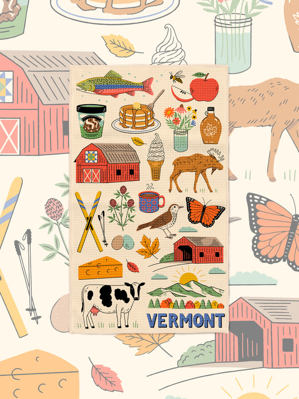 Vermont icon kitchen towel styled over a matching illustrated backdrop of barns, butterflies and fall leaves