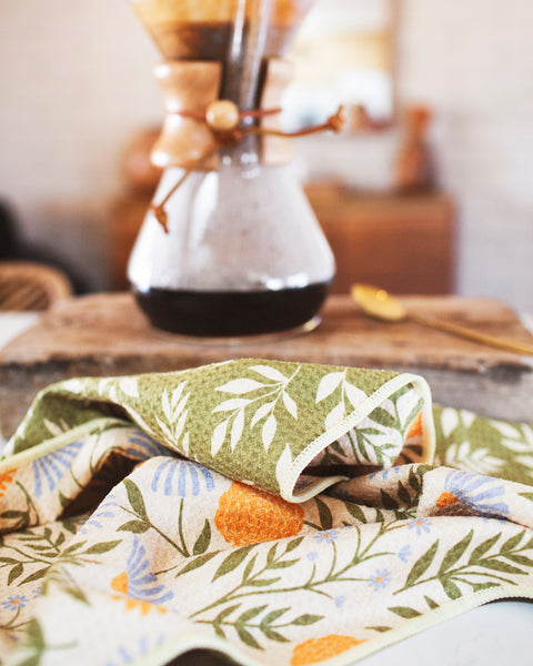 Wavy Flowers Kitchen & Tea Towel on a kitchen counter with coffee maker in the background.