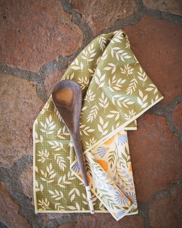 Wavy Flowers Kitchen & Tea Towel with a wooden spoon on a rustic background.