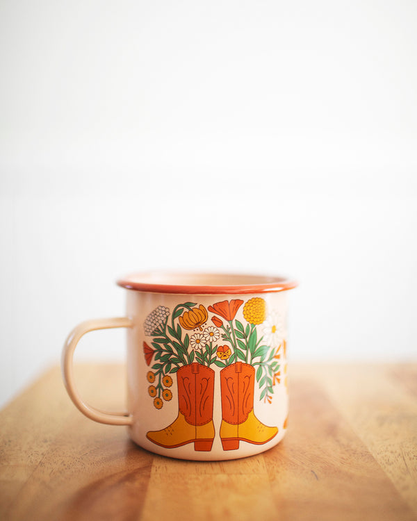 Western Bloom Enamel Mug 16oz with floral boot design by Trek Light on a wooden table, perfect for cozy sips.