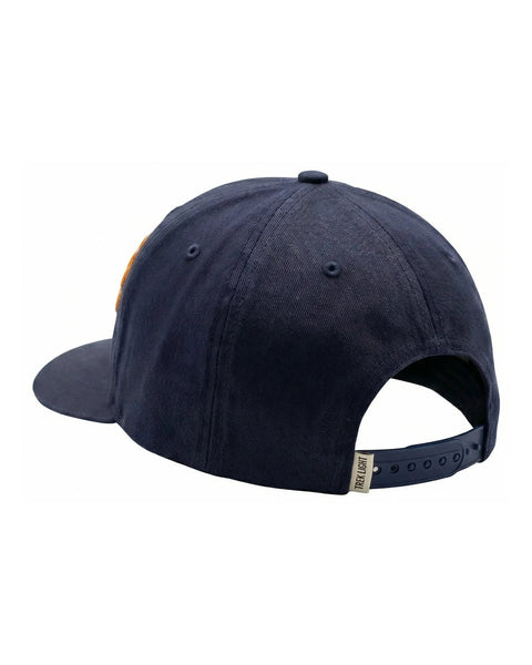 Wild Thing Kids Hat in navy cotton twill, seen from the back with a snap strap and a tan patch peeking at the side, on white.