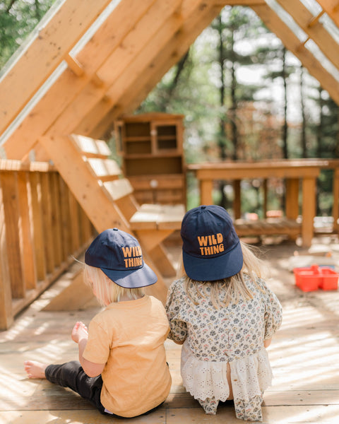 Kids wearing Wild Thing Kids Hats, enjoying playtime outdoors in a sunlit play area.