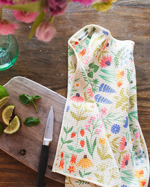 Wildflower Wonder Kitchen & Tea Towel on wooden surface with lemons and limes, showcasing its vibrant, eco-friendly design.