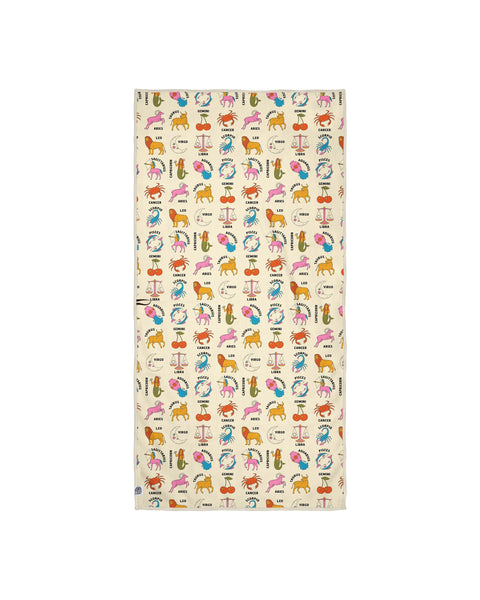 Zodiac patterned towel on cream background with scattered zodiac icons including lion, crab, scales, ram, and fish symbols in playful watercolor style