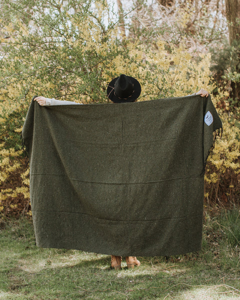 Cozy Humboldt Blanket by Trek Light, handwoven with recycled materials, held by person in nature; one tree planted per sale.