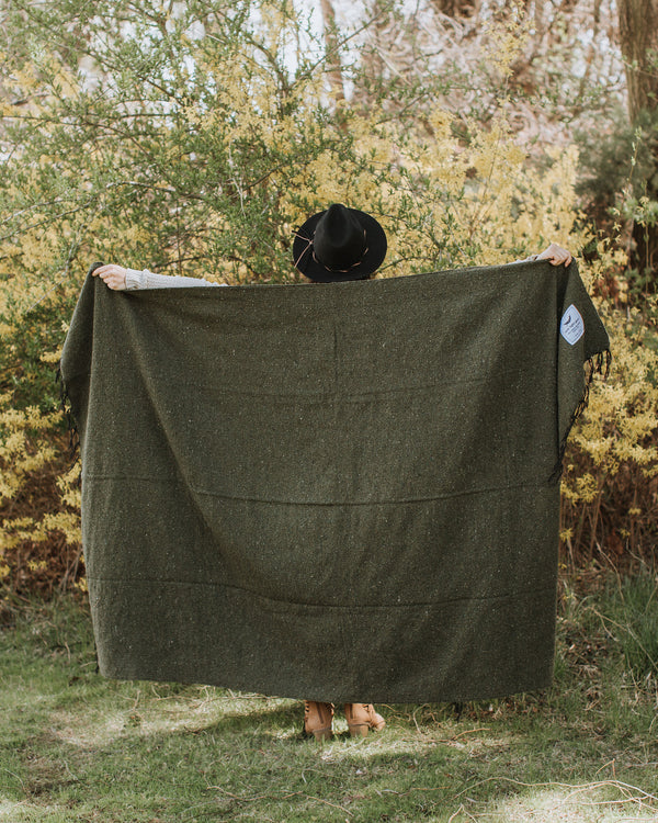Cozy Humboldt Blanket by Trek Light, handwoven with recycled materials, held by person in nature; one tree planted per sale.