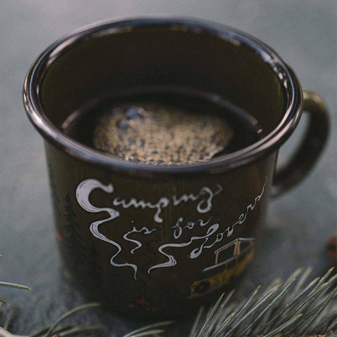 Trek Light Camping Is For Lovers enamel mug with coffee, surrounded by nature, perfect for adventurers and coffee lovers, 12oz.