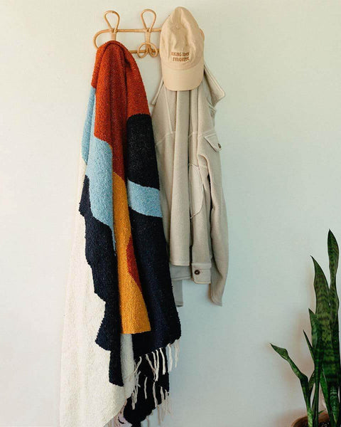 Cozy handwoven Mountains Blanket by Trek Light hanging stylishly in a home, ready to bring warmth and art to your space.