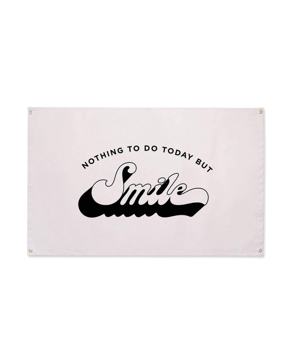 Nothing To Do Today But Smile Canvas Flag in pale pink with black retro script lettering and brass grommets, on white.