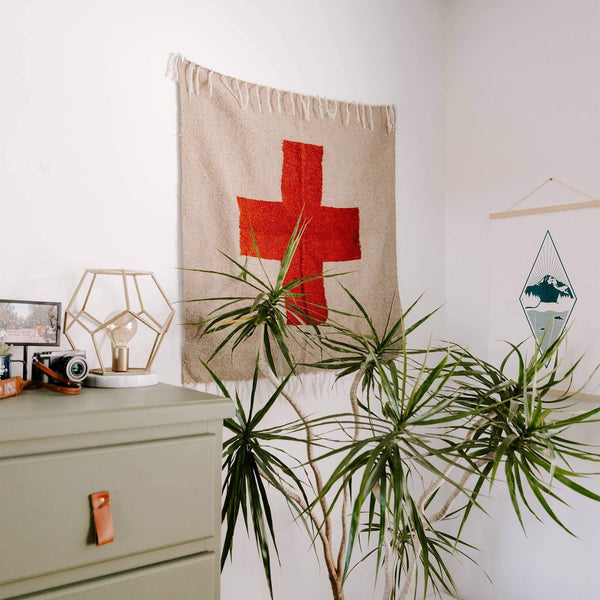 Trek Light Positive Vibrations Blankestry hanging in a cozy room with plants, adding warmth and style. Eco-friendly and versatile decor.