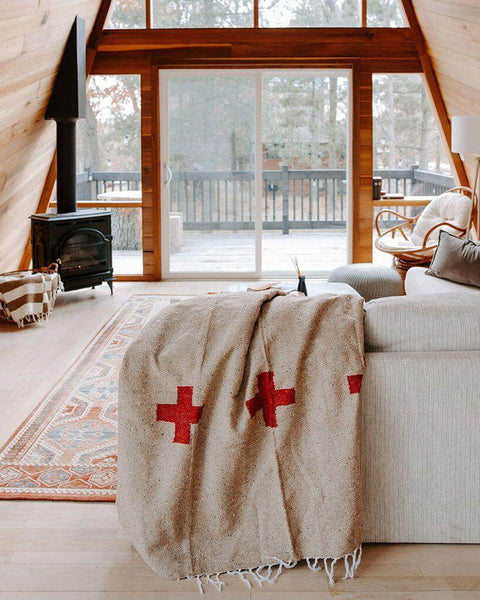 Cozy cabin interior with a Trek Light Positive Vibrations Blanket draped over sofa, showcasing sustainable, handwoven charm.