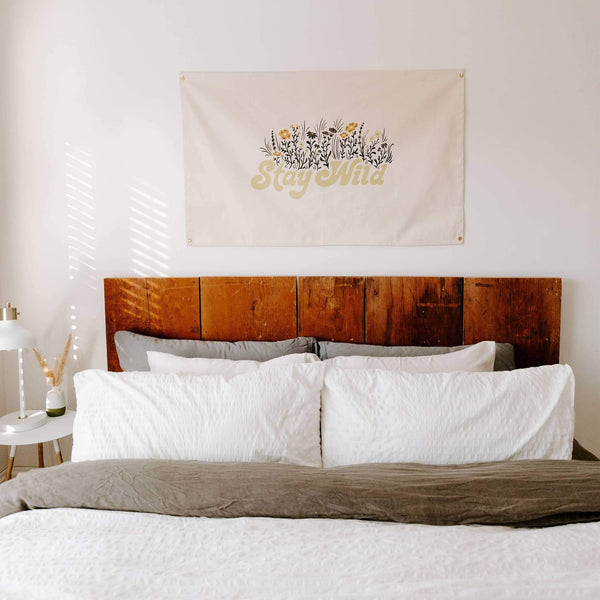 Stay Wild Canvas Flag by Trek Light hanging above a cozy bed, made from 10oz Cotton Canvas with hand-screened ink prints.