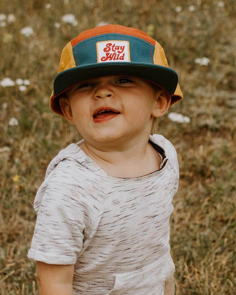 Toddler wearing colorful Stay Wild Trek Light kids hat, perfect for outdoor adventures. 5-panel camper style. Youth sizes available.