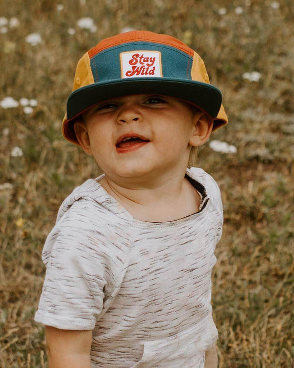 Toddler wearing colorful Stay Wild Trek Light kids hat, perfect for outdoor adventures. 5-panel camper style. Youth sizes available.