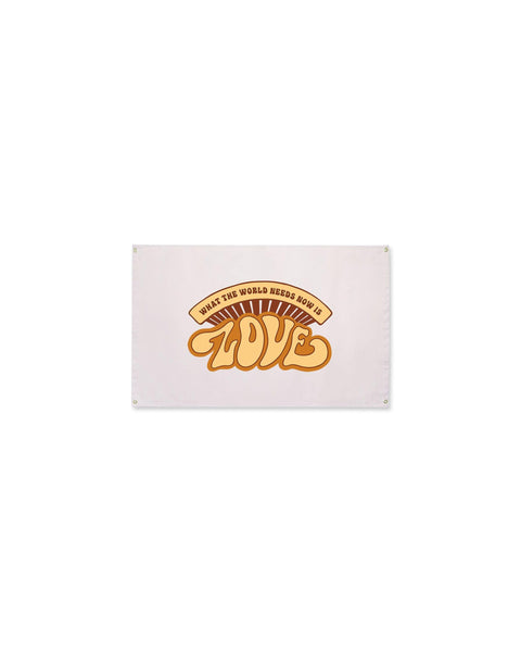 What The World Needs Now Canvas Flag in cream with a retro orange and brown "Love" graphic and grommets, on white.