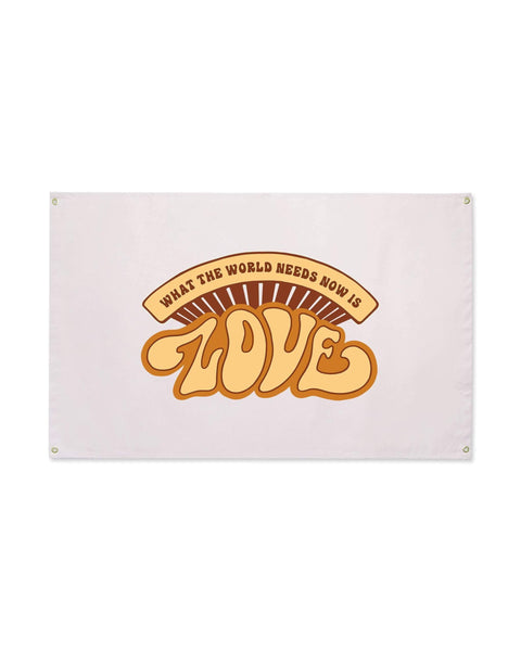 What The World Needs Now Canvas Flag in pale blush with a retro orange and tan "LOVE" graphic and grommets, on white.