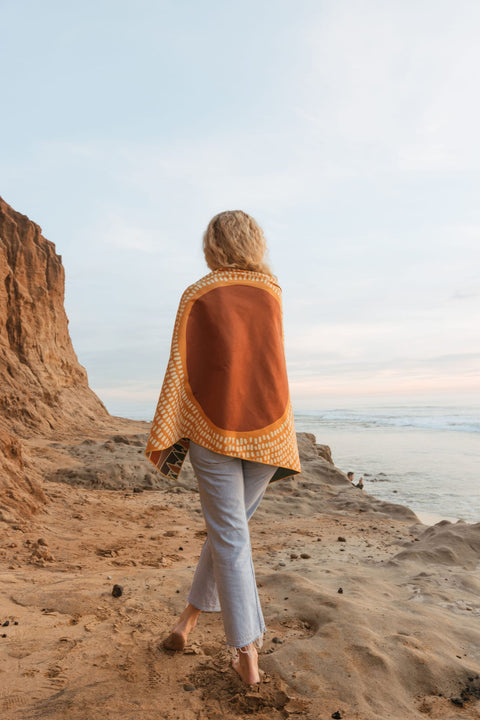 Alpenglow Wander and Travel Towel held open on a coastal cliff at sunset