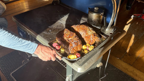 Two deliciously cooked steaks on a tray with colorful vegetables in a rustic kitchen setting.