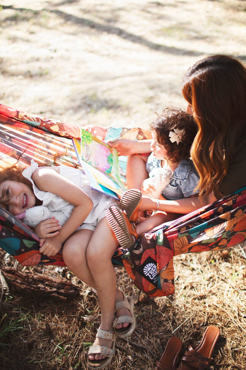 A family reading together in a Trek Light mushroom print hammock