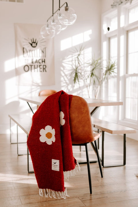 A colorful handwoven Trek Light blanket draped over a chair in a sunlit room