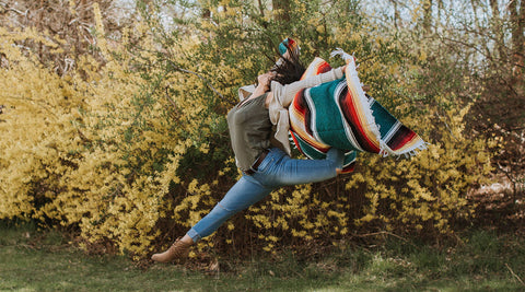 Person wrapped in a colorful Trek Light handwoven blanket outdoors