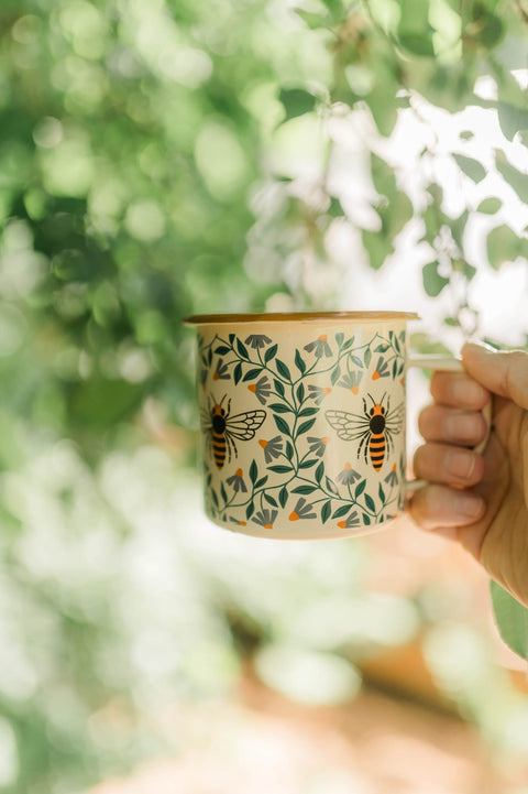 Honey Bee Enamel Mug 16oz held in hand outdoors on a slow camp morning