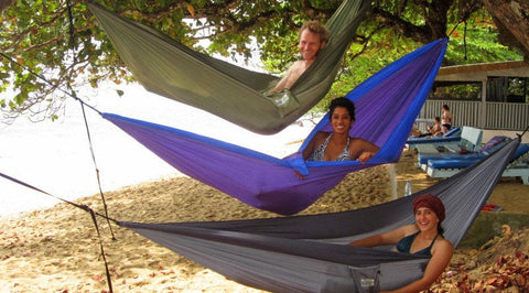 Three Peace Corps volunteers relaxing in a triple decker of Trek Light hammocks strung in a mango tree on the beach in Kribi, Cameroon