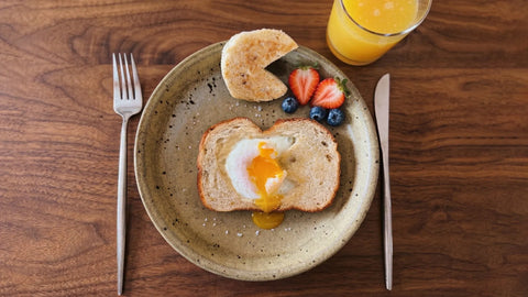 The Weekly Light Vol 21 breakfast featuring toast, poached egg, fruit, and a glass of orange juice.