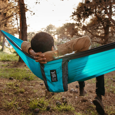 A Trek Light double hammock hung between trees in a quiet forest