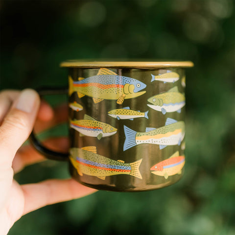 Trout enamel camp mug with a colorful fish design at a campsite