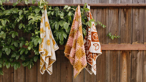 Colorful Trek Light towels hanging on a wooden fence, showcasing stylish designs and technical performance for versatile use.