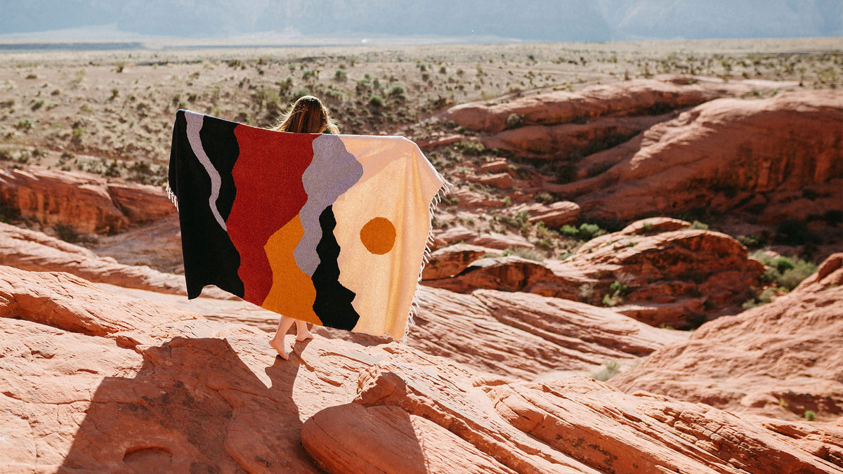 Trek Light Deluxe Pattern Blanket in a colorful design, displayed in a picturesque desert landscape for cozy adventures.