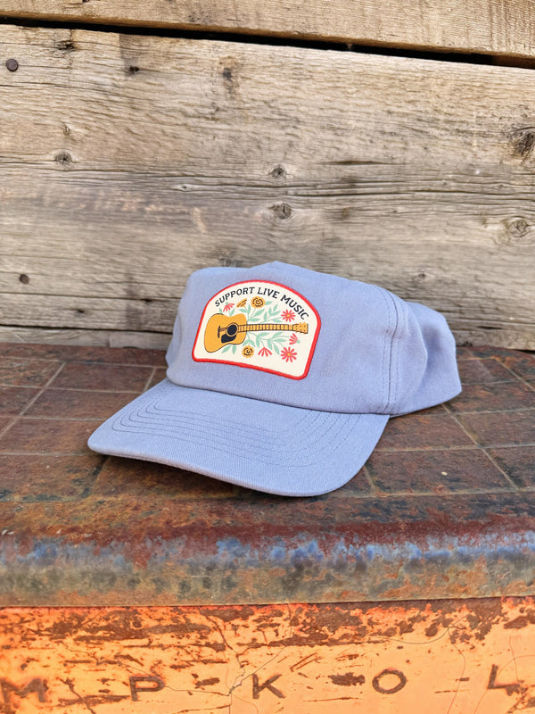 Support Live Music Hat displayed on a rustic surface with a guitar logo, perfect for music lovers.