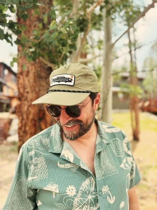 Man wearing a Trout Hat (Olive) outdoors, enjoying nature and looking stylish.