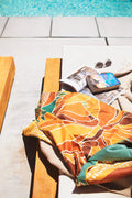 Alpenglow Wander Towel draped on a lounge chair by the pool, showcasing warm tones and mountain vibes.