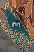 Vintage camera resting on a colorful Trek Light blanket with geometric patterns, capturing the essence of creative outdoor photography.