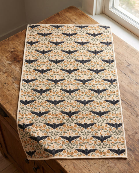 Bats & Blooms waffle kitchen tea towel laid flat on a wood counter showing the full front print