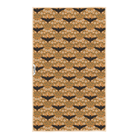 Reverse side of Bats & Blooms tea towel in golden mustard with black bats, white blooms and Trek Light tag