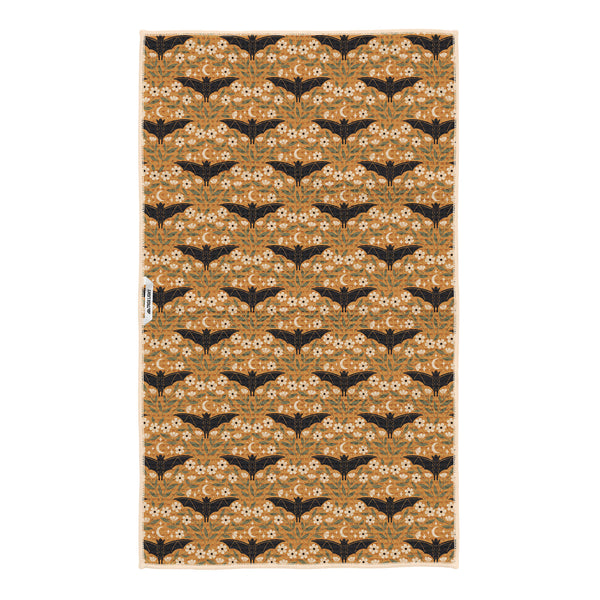 Reverse side of Bats & Blooms tea towel in golden mustard with black bats, white blooms and Trek Light tag
