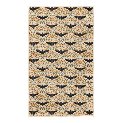 Bats & Blooms kitchen tea towel in cream with black bats, orange marigold flowers, green leaves and crescent moons