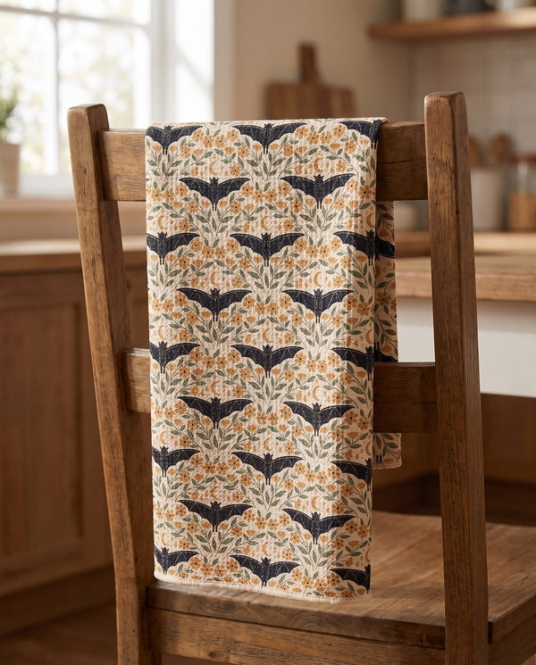 Bats & Blooms waffle kitchen tea towel draped over a wooden kitchen chair, front print facing out