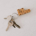 Wooden keychain with 'Be Kind' design, attached to keys. A Trek Light gift idea, featuring hand-cut wood and nickel hardware.