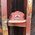Be The Light Hat displayed on a rustic rack, showcasing its unique design and message.