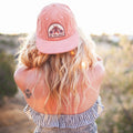 Woman wearing a Be The Light Hat, showcasing its stylish design and adjustable fit in a sunny outdoor setting.