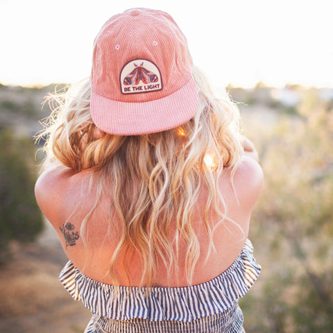 Woman wearing a Be The Light Hat, showcasing its stylish design and adjustable fit in a sunny outdoor setting.